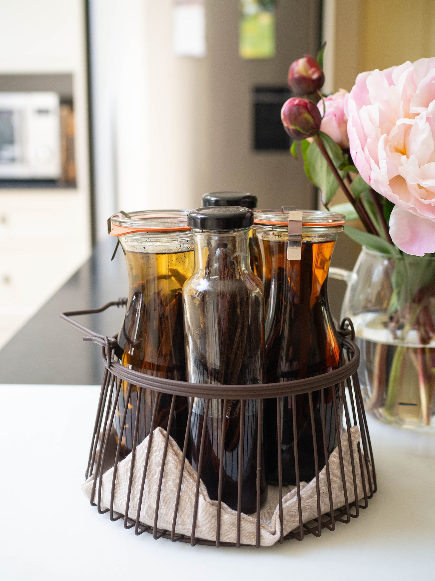 four bottles of homemade vanilla extract in wire basket