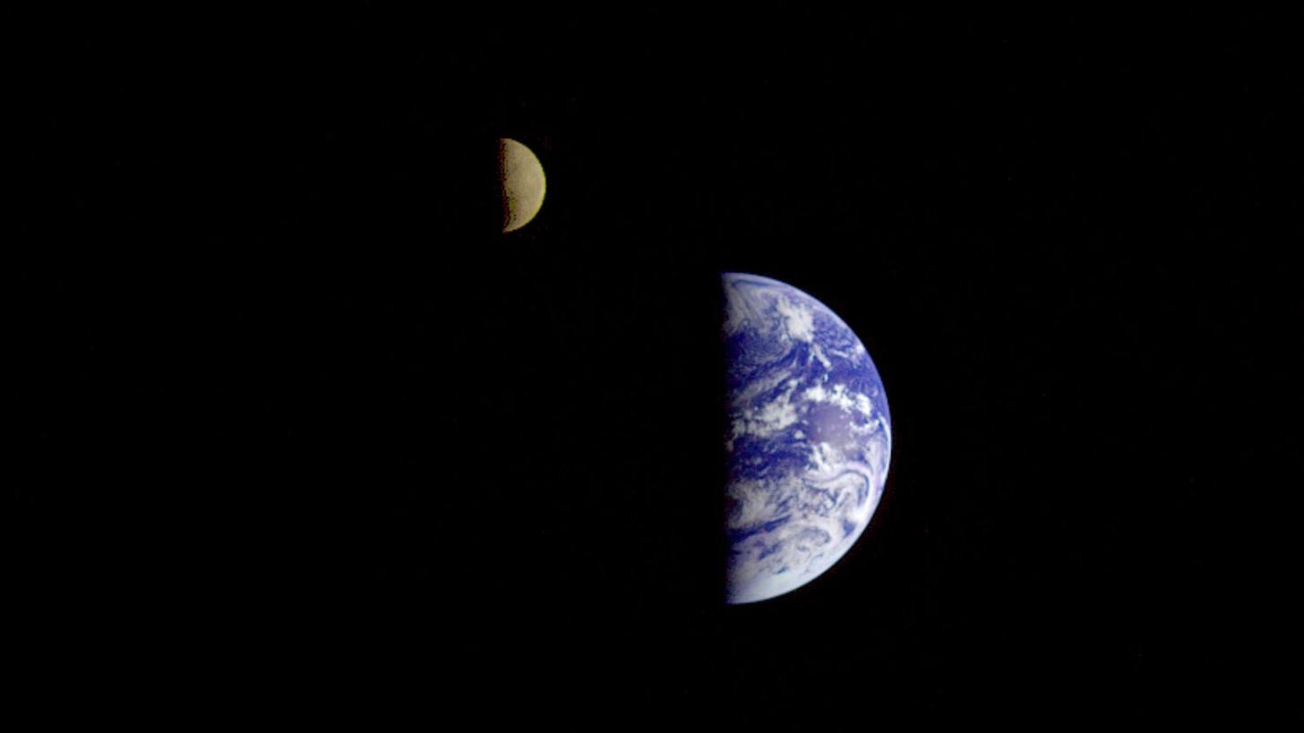 The Earth and the Moon side by side with their left halves in darkness.