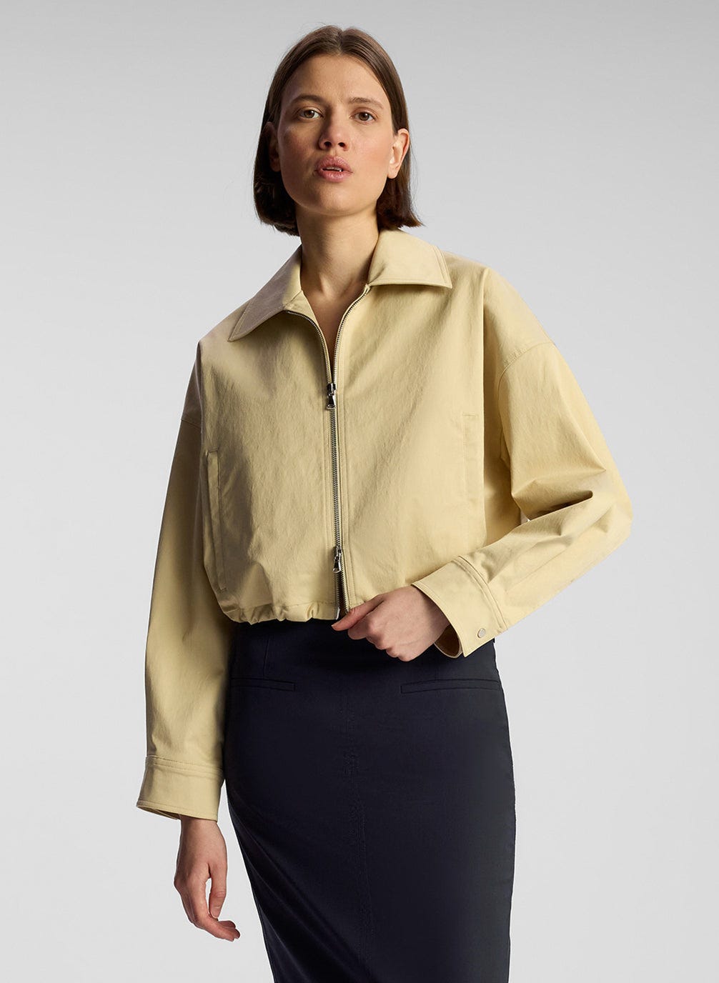 front view of woman wearing tan jacket and navy blue maxi skirt