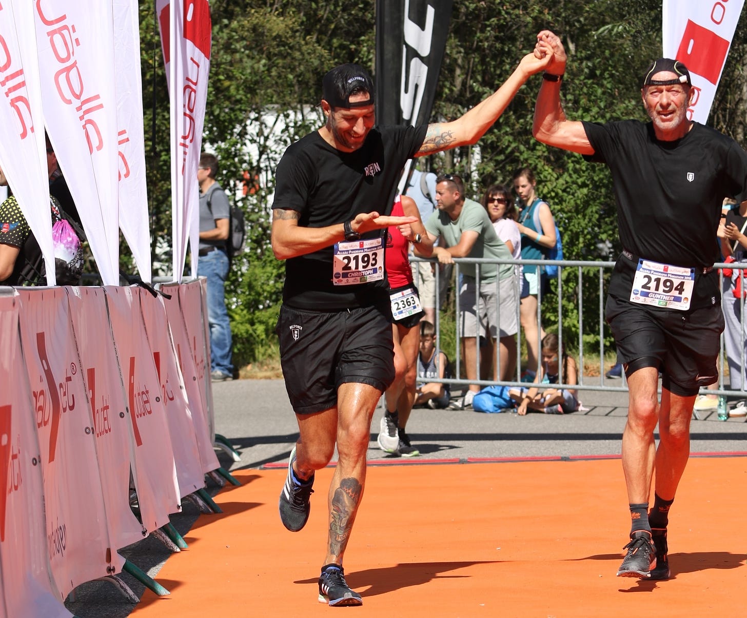 The author and his father crossing the finish line hand in hand at the Allgäu Panorama Marathon
