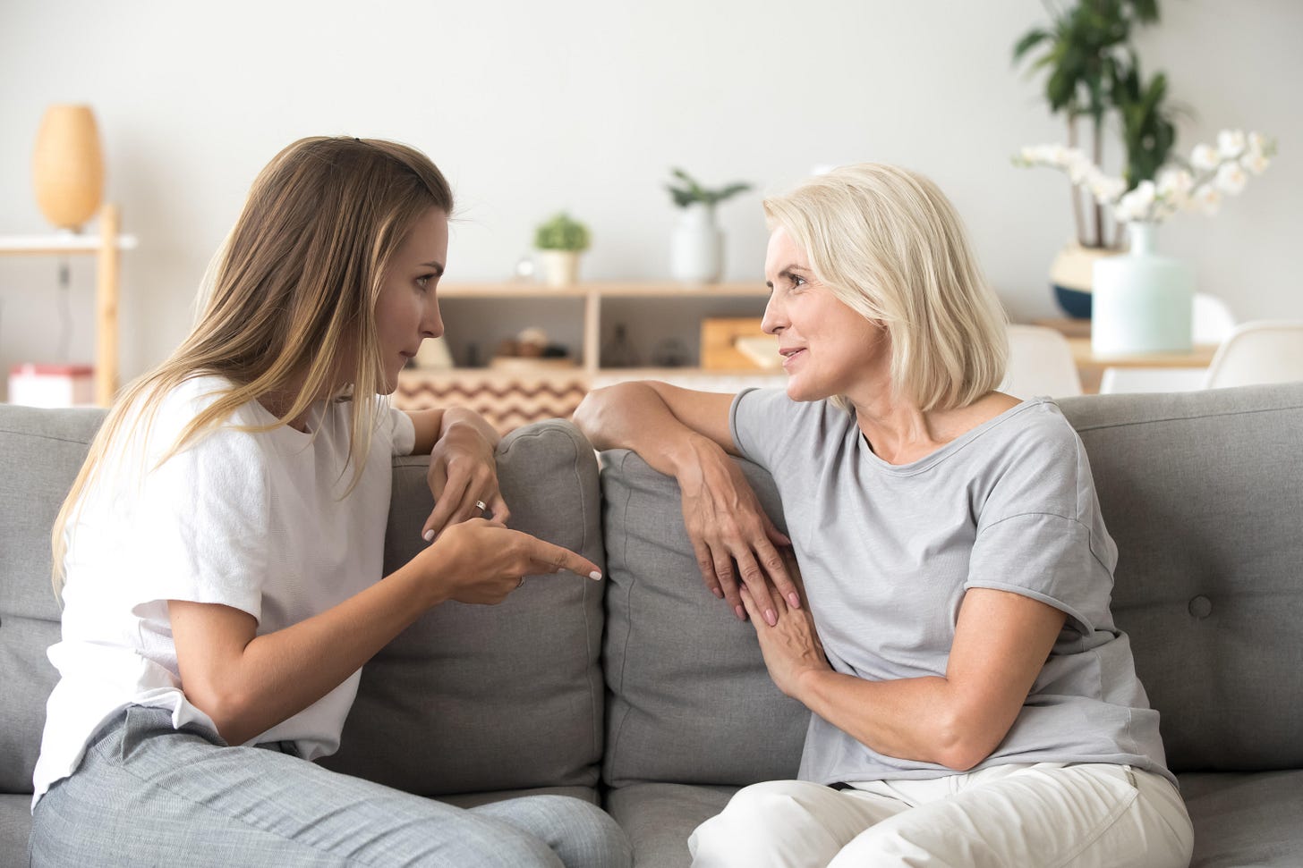 Two women sat on a sofa having a serious conversation 