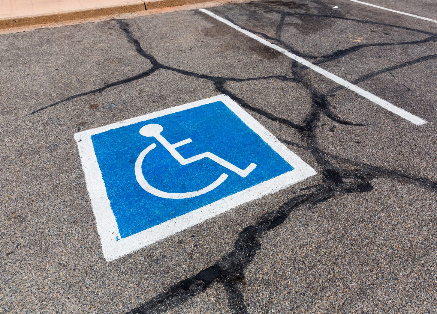 Wheelchair symbol painted onto paveement to mark parking space