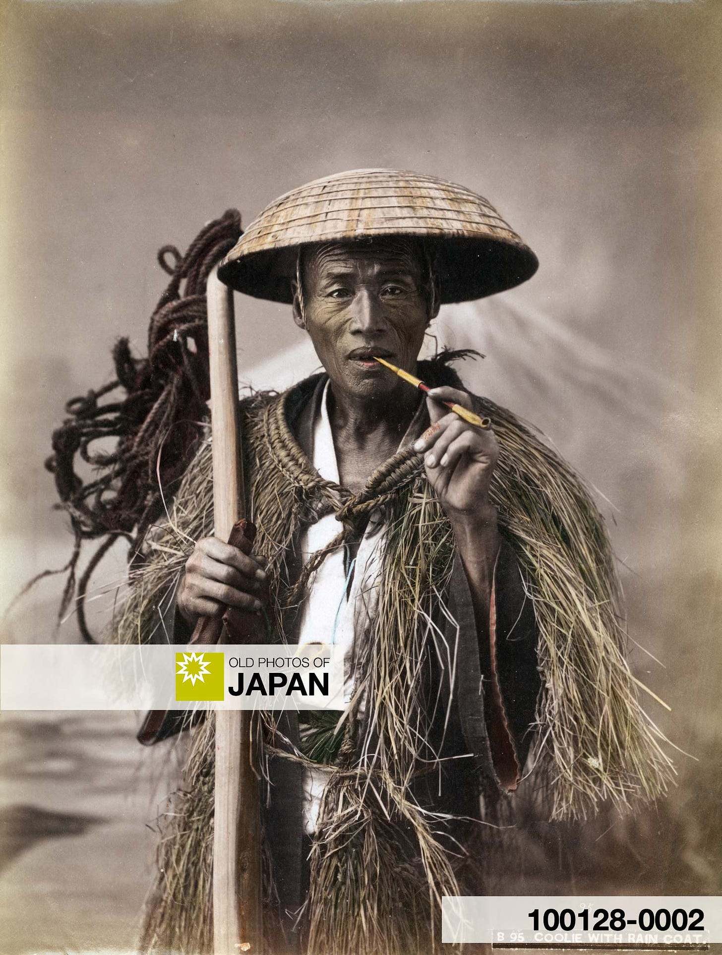 Japanese Farmer with pipe, wearing a straw raincoat and conical hat
