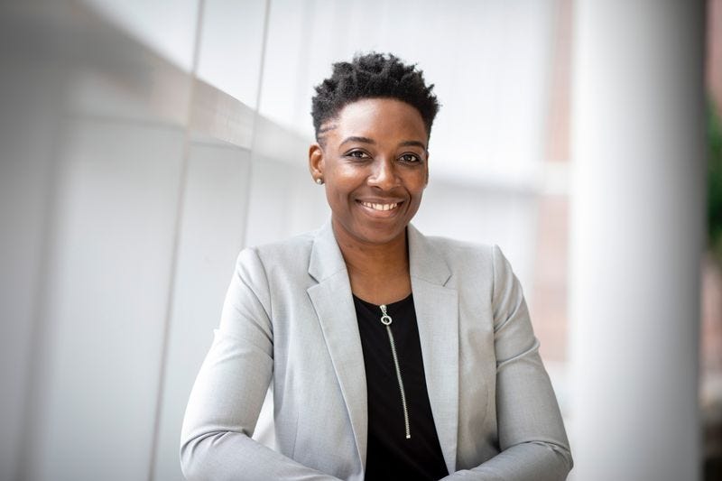 Dark-skinned person wearing a business suit smiling