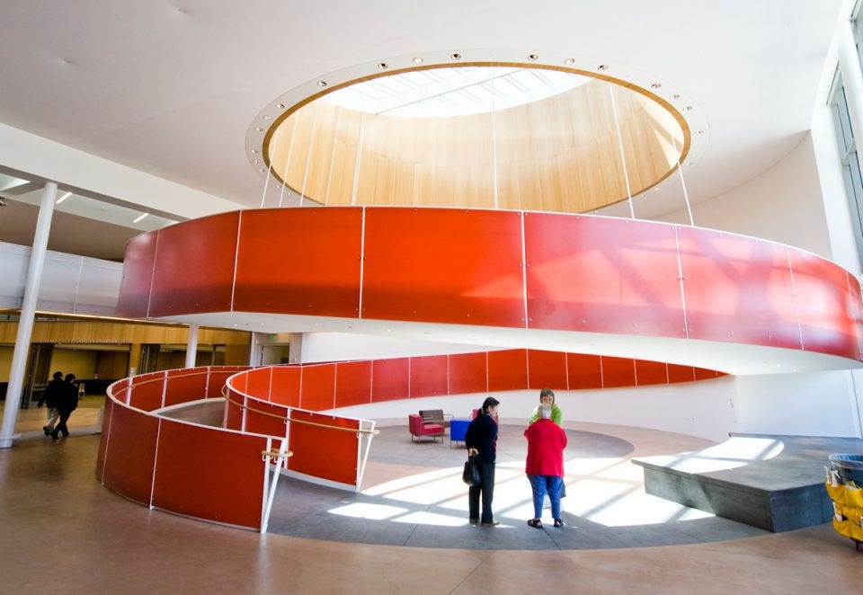 The bright red helix-style ramp at the Ed Roberts Campus, University of California, Berkeley. The ramp is the centerpiece of a brightly lit atrium, a front-and-center celebration of accessible architecture.