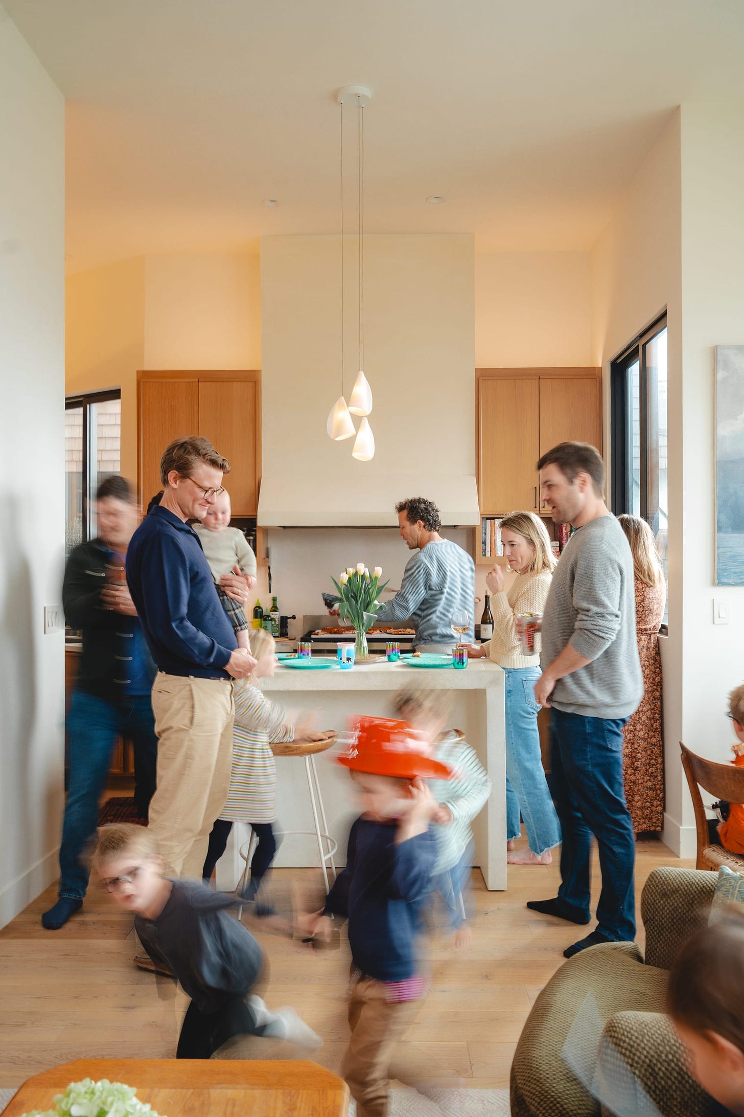 a modern kitchen full of life. many adults and kids moving around