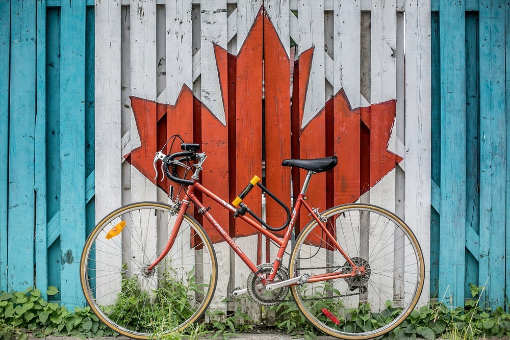 canadian flag painted on a fence with a bike standing in front of it