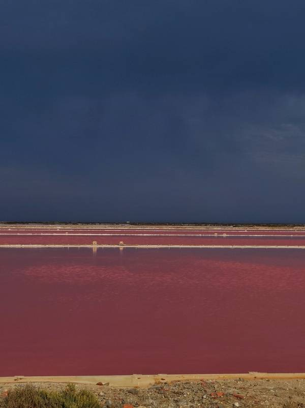 The pink of the salt pans of Gruissan, in France, shines beneath a stormy sky. Why do I travel? To see more extraordinary colours in nature.