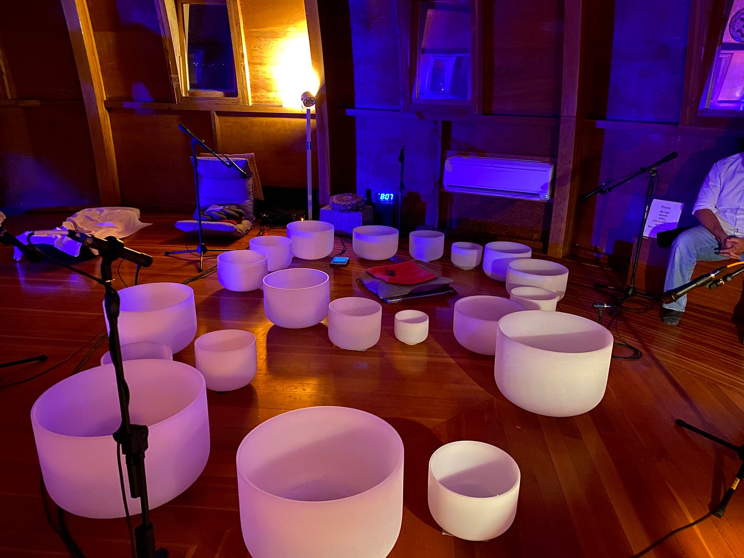 White crystal singing bowls lay on a wooden floor.