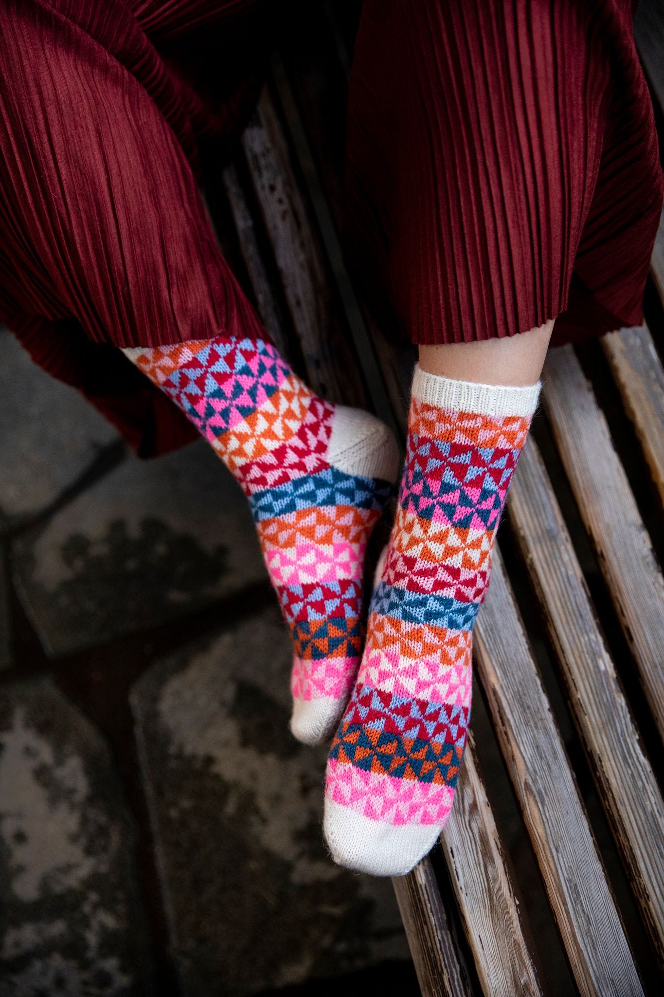 A pair of brightly-colored socks displayed on someone's feet - you can see the side of the right foot and the top of the left, showing off a multi-colored design that might remind the viewer of foil pinwheels