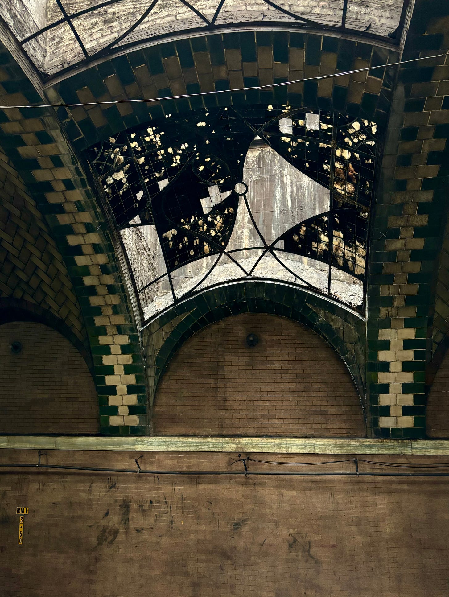 Green tiled arches cross what were once very ornate windows above the brick wall of the station.