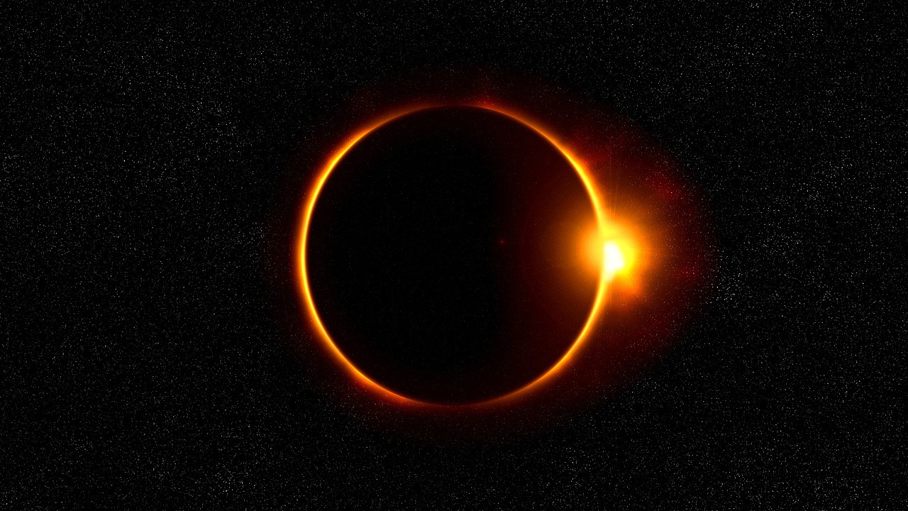 Photo of total solar eclipse, a black image with a ring of gold light outlining the sun with the moon in front of it and a flare of light on the right side of the sun.