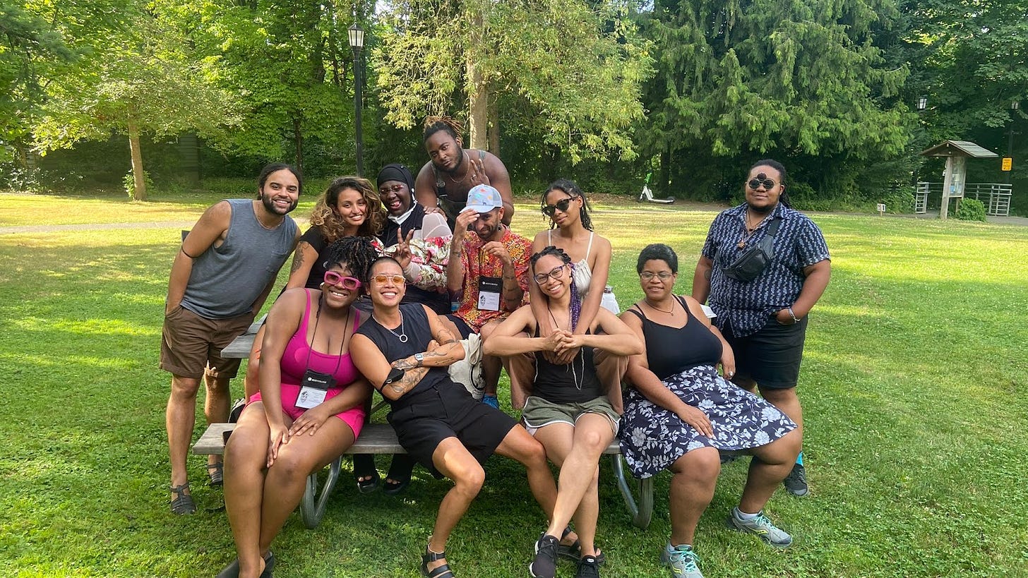 KB alongside other cute queers of color sitting at a picnic table.