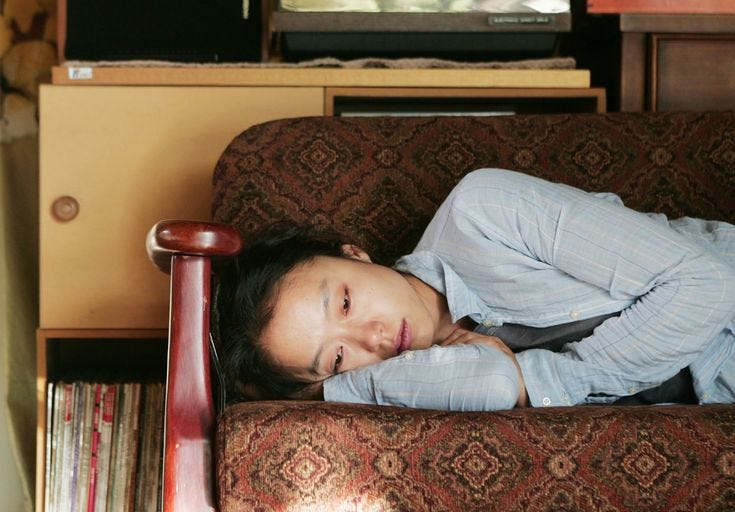This may contain: a young woman laying on top of a couch next to a book shelf filled with books