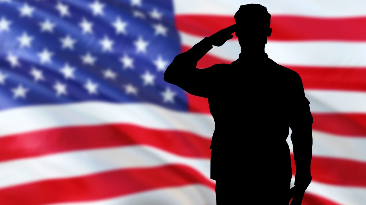 A soldier saluting in front of the U.S. flag.