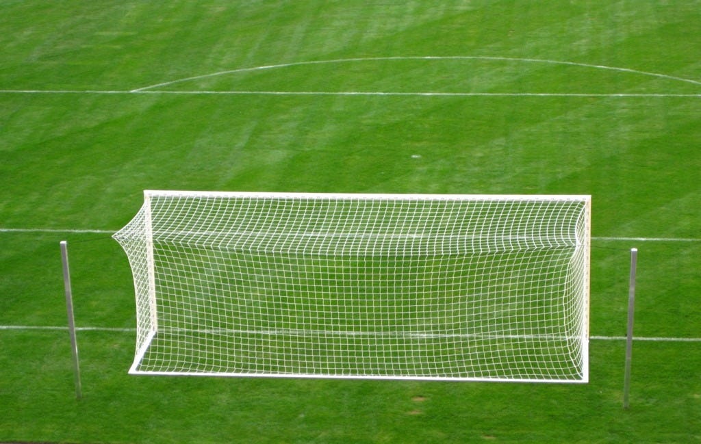 A soccer goal on a lined green field.
