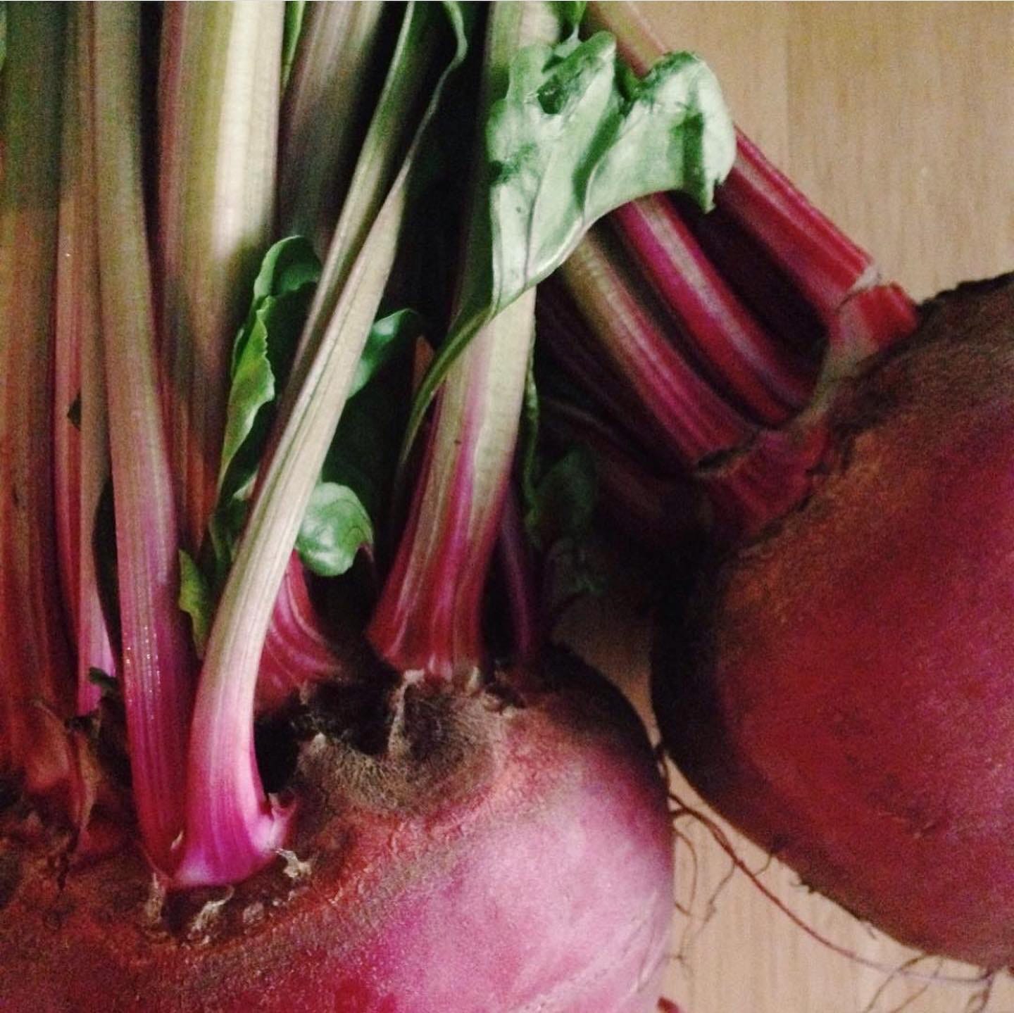 a close up shot of red beets and their green stems