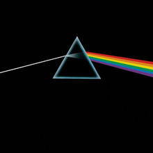 A prism refracting white light into a rainbow on a black background