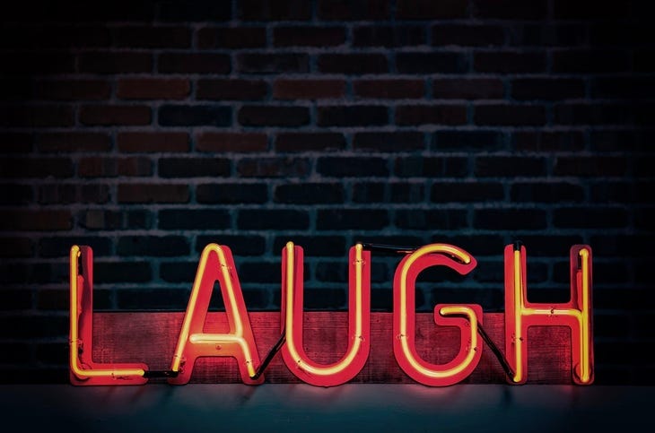 A neon sign: 'Laugh'