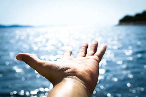 Free Person Hand Reaching Body of Water Stock Photo