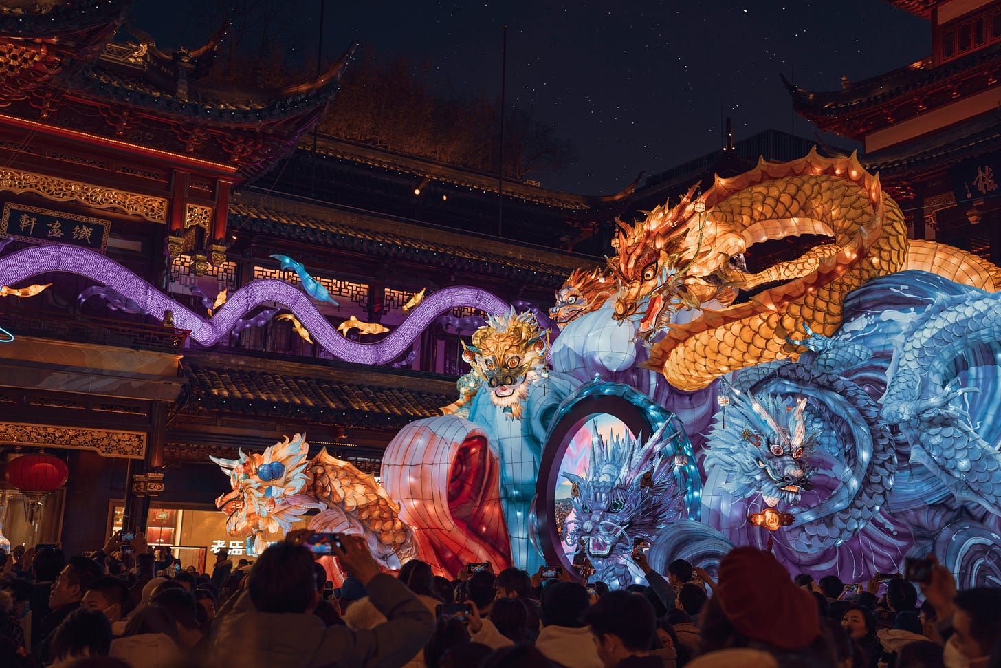 Fotografia em cores de apresentação em templo chinês assistida por um grupo de pessoas. Uma enorme lanterna de papel representa diferentes dragões chineses.