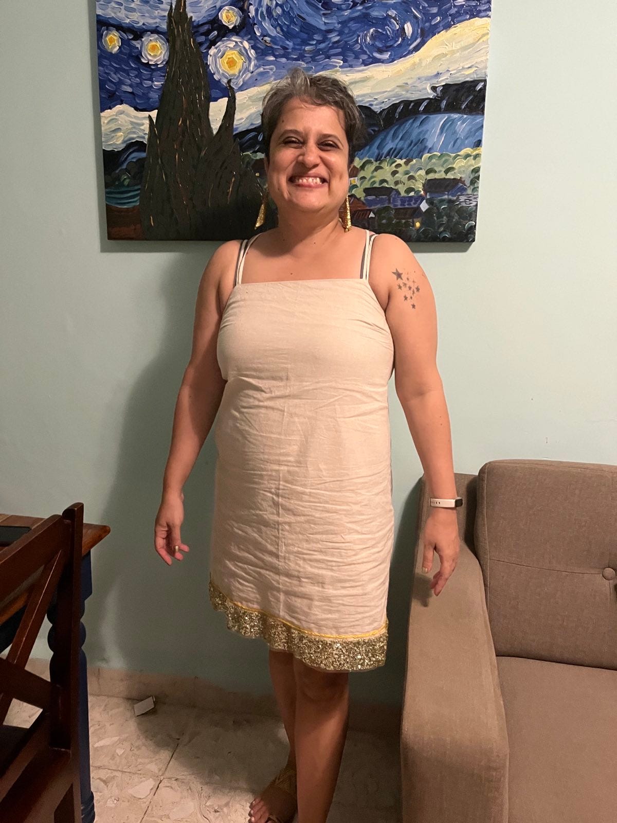 me in a short beige dress with sequins at the hem. a copy of Van Gogh's Starry Night is on the wall behind me.
