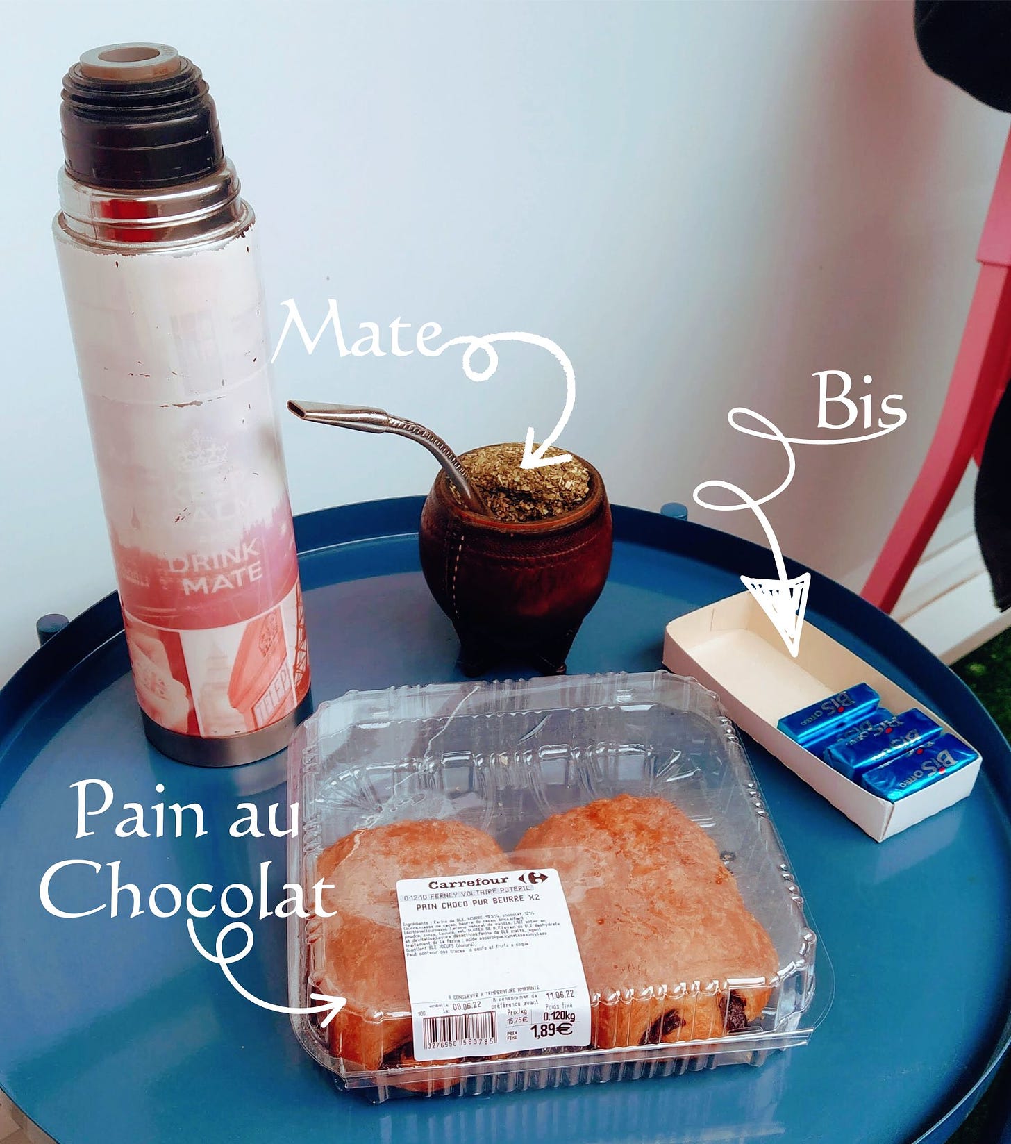 My thermos and mate on a little round table, besides a half empty box of chocolate wafers and a transparent plastic box with 2 pain au chocolat inside.