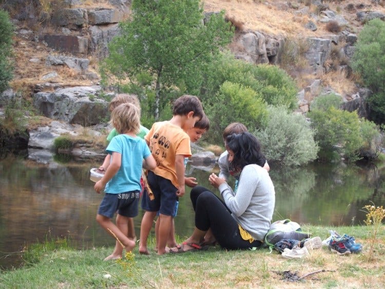 Niños observando bichos en el rio