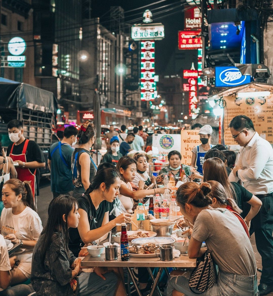 a group of people sitting at a table in the middle of a street