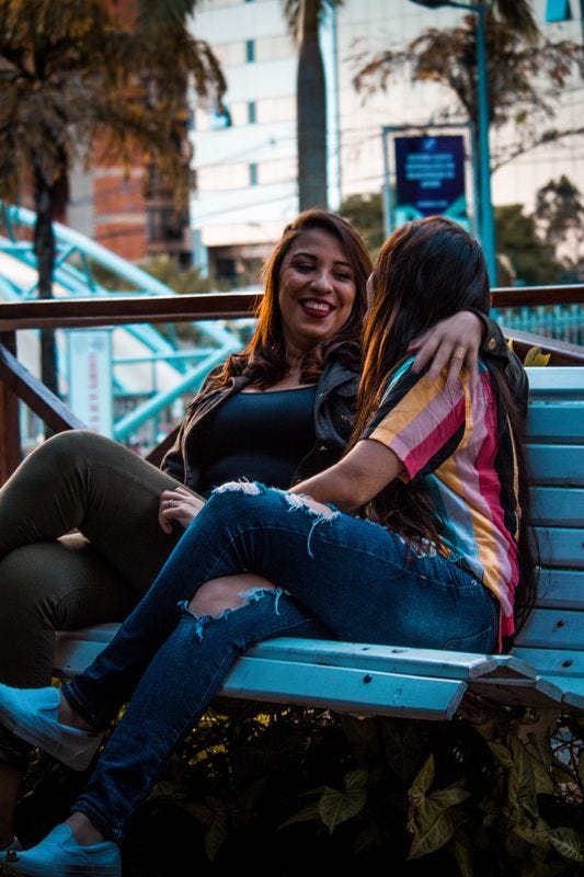 Two people sitting on a bench together laughing