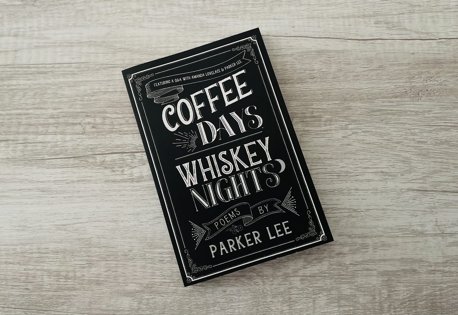 a photo of parker's book "coffee days whiskey nights" sitting on a llight gray wooden surface. this version lists "parker lee as the author"