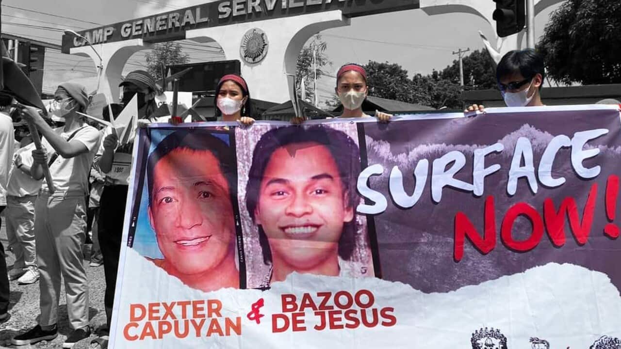 Against a black-and-white background, two women and a young man, all wearing medical masks, hold a banner that reads 'Surface Now!' and depicts portraits of two Filipino men and their names: Dexter Capuyan and Bazoo De Jesus. The image has been digitally altered. 