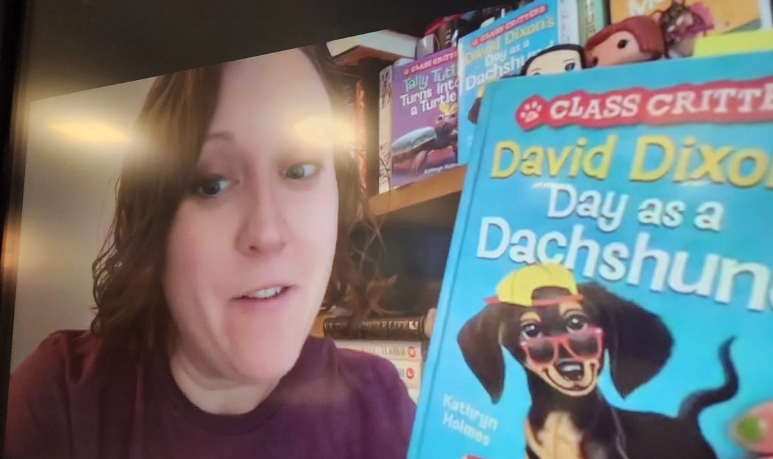 Kathryn holding up a copy of David Dixon's Day as a Dachshund on camera