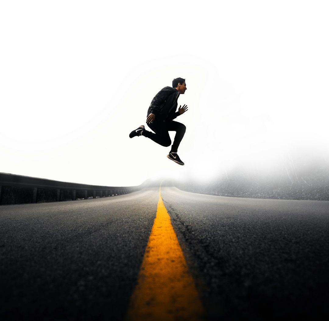 man jumping above gray and yellow concrete road at daytime