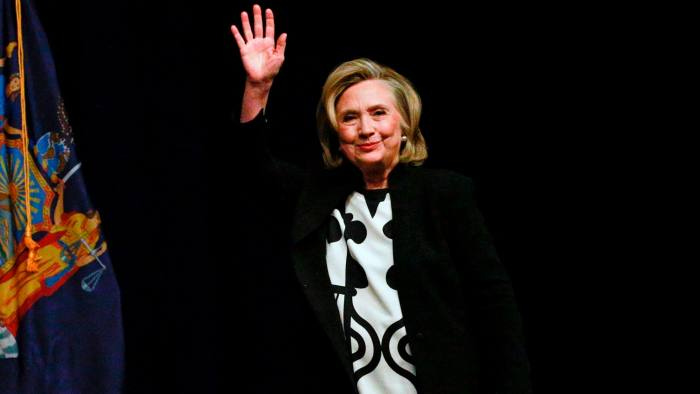 Hillary Clinton waving against a black background