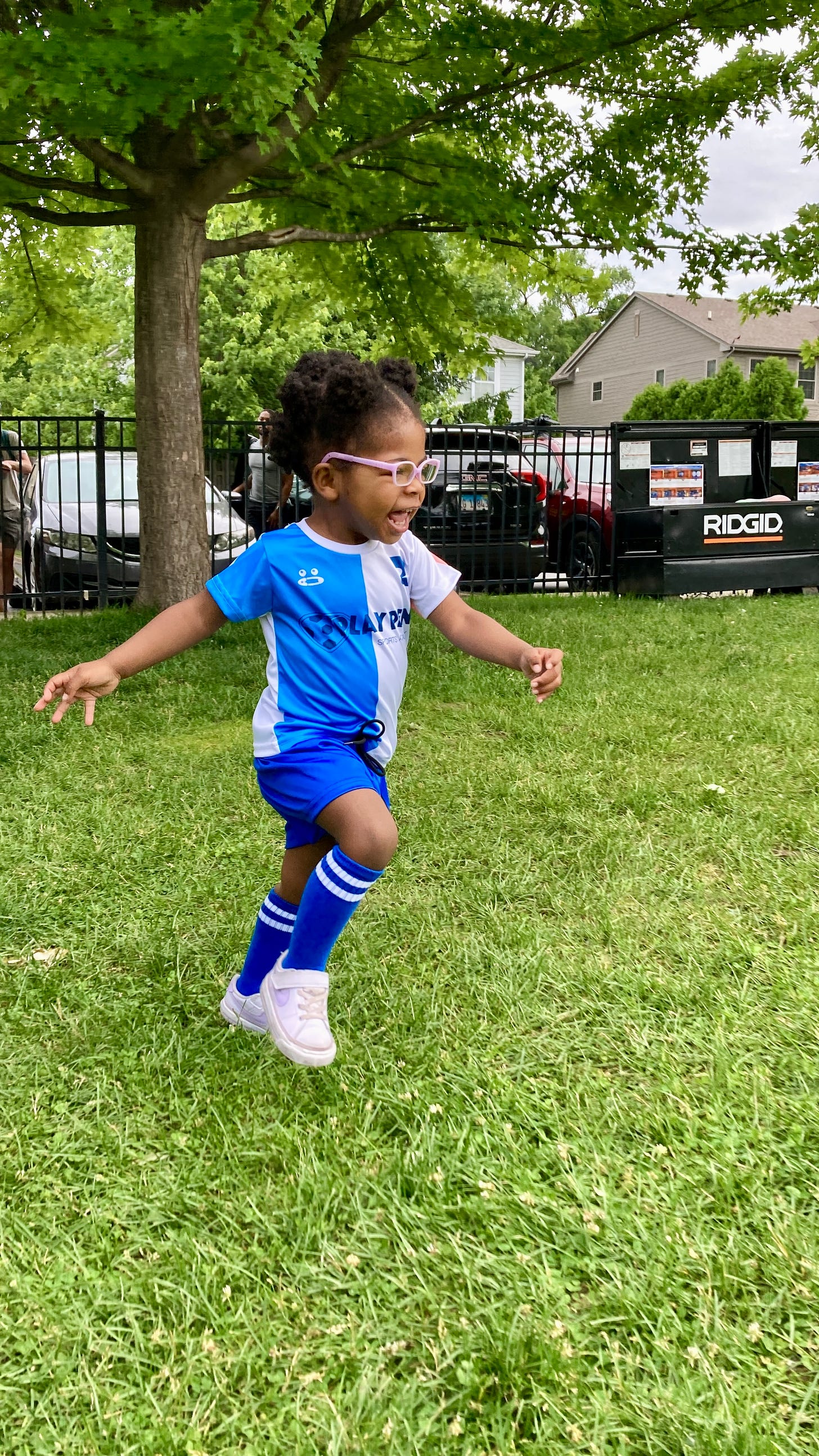 Picture of a Black toddler girl running in her soccer uniform