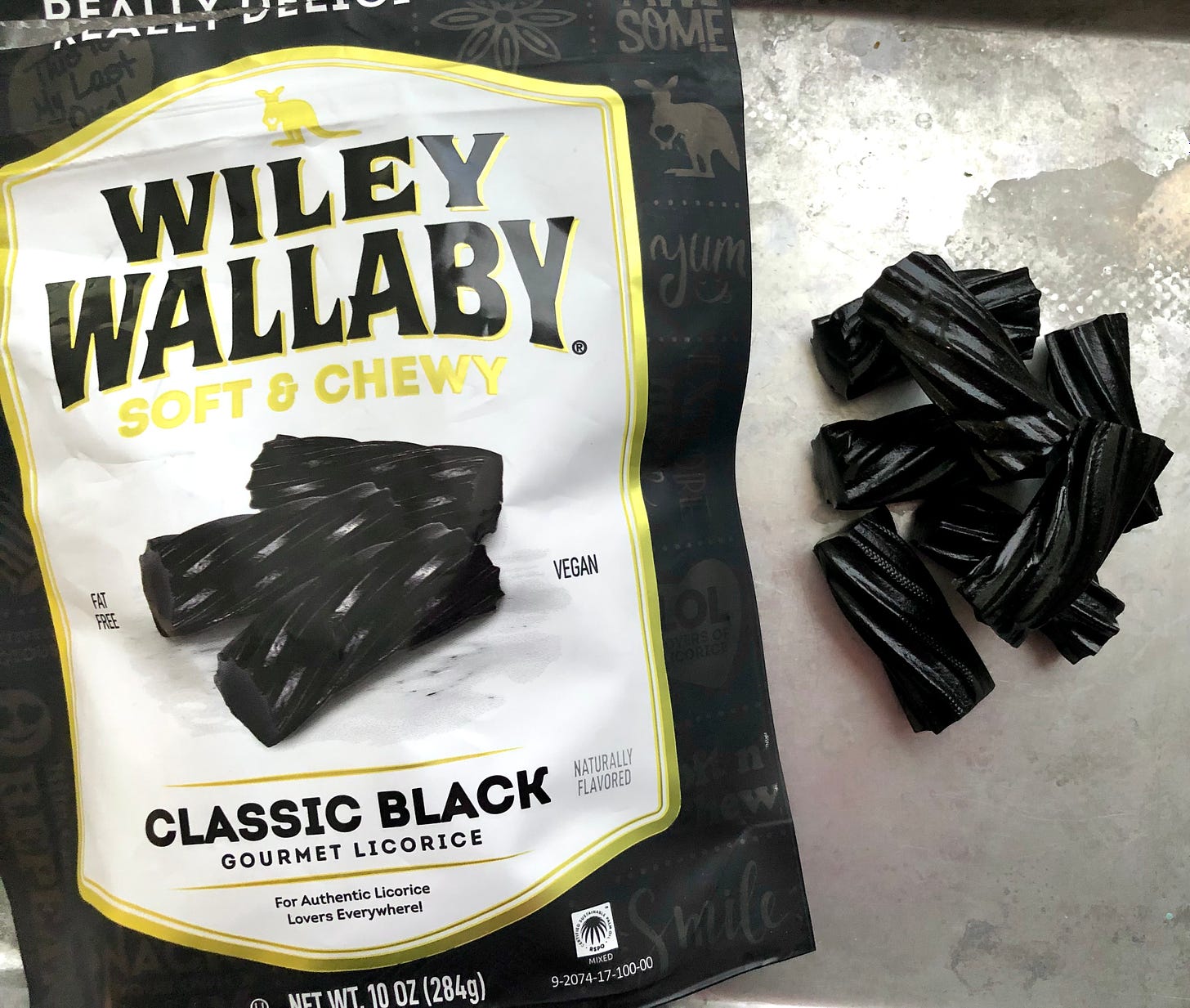 a package of Wiley Wallaby brand classic black licorice, with some black licorice twists on a plate