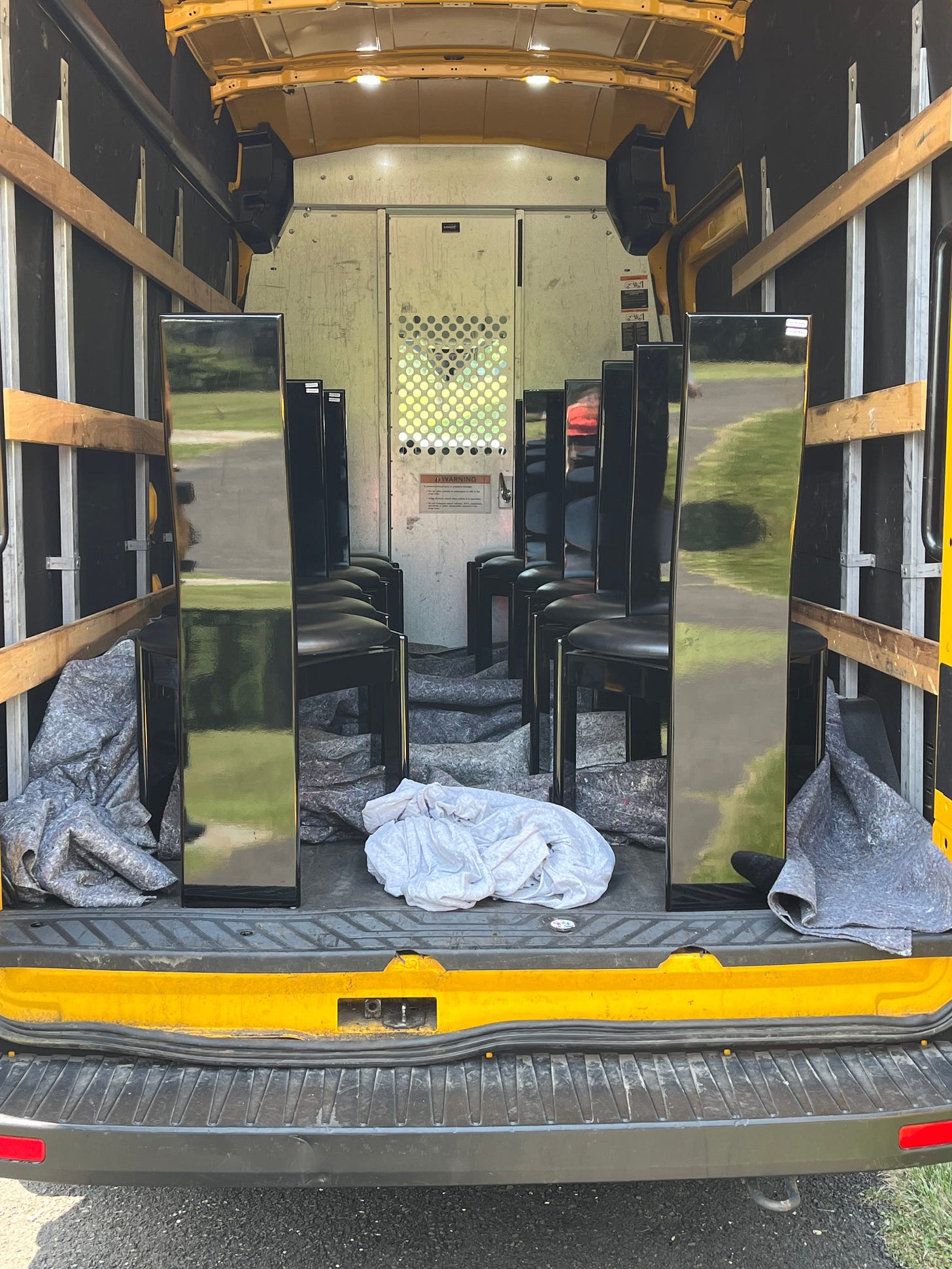 12 modern dining chairs in the back of a cargo van.