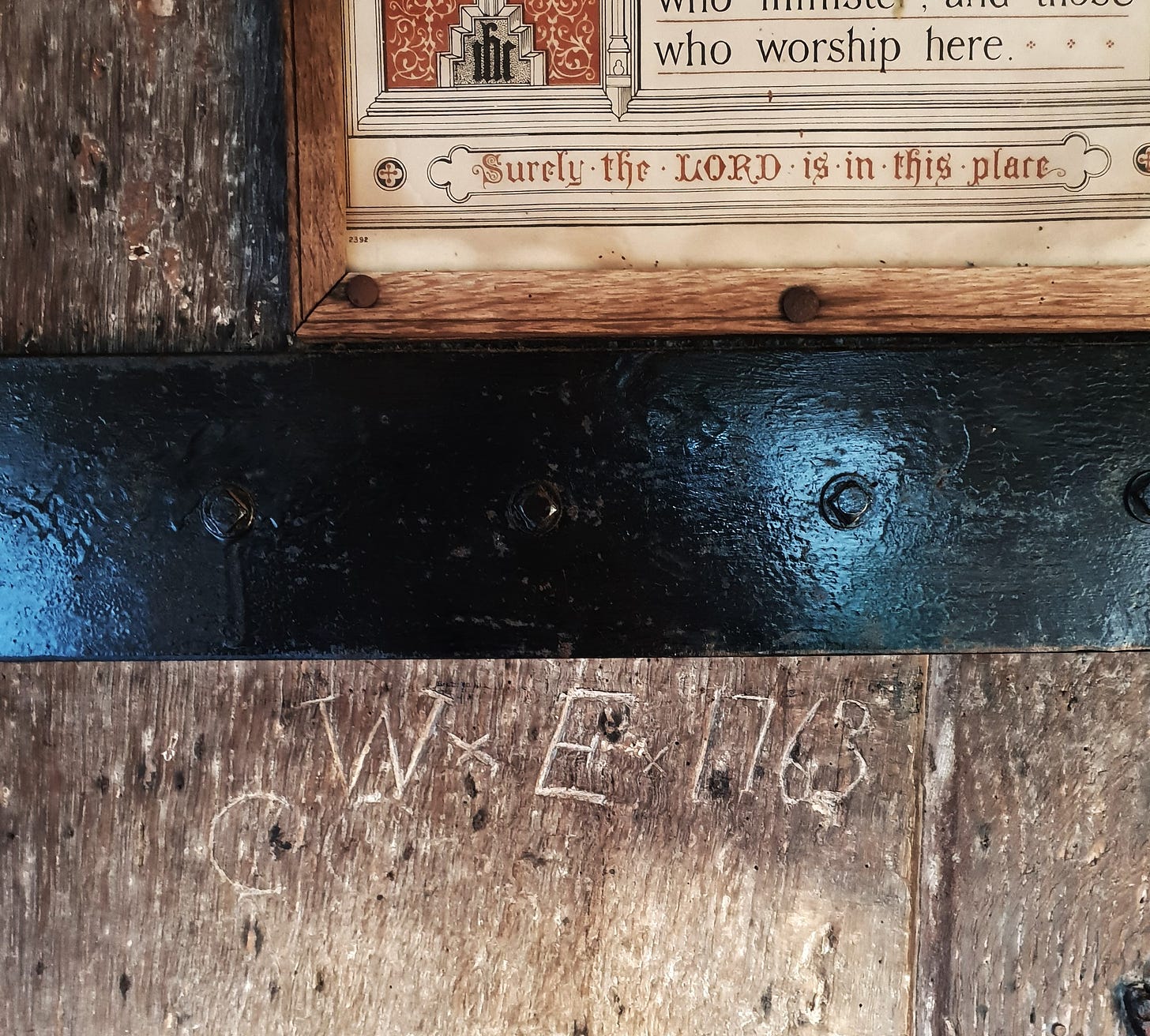 The letters 'W' and 'E' and the year 1763 scratched into an ancient wooden church door