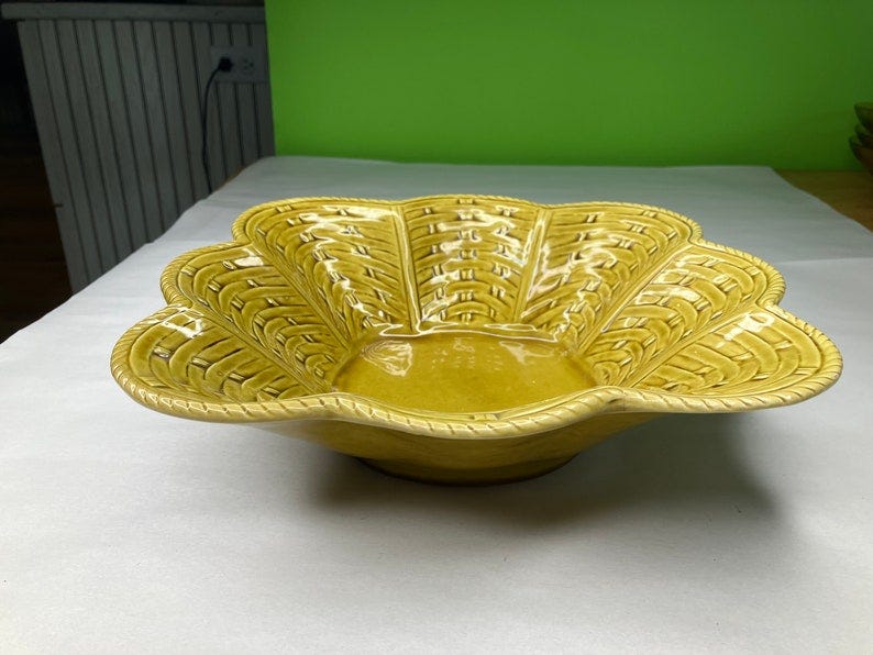 May include: A yellow ceramic bowl with a woven design. The bowl has a scalloped edge and is shaped like a flower.