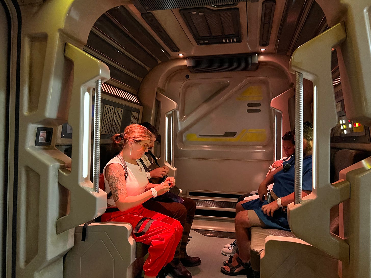 Four people sitting in a fictional small transport shuttle
