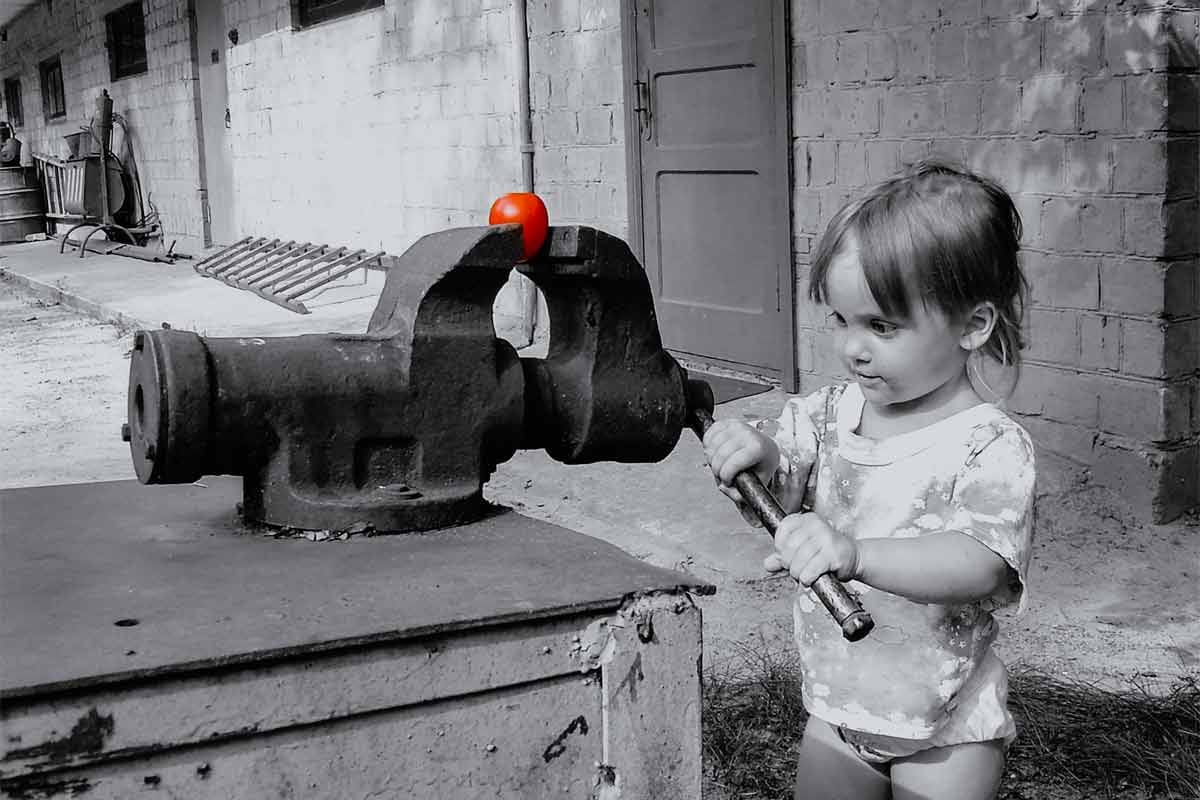 A child squeezing a perfectly ripe tomato in a vise grip.