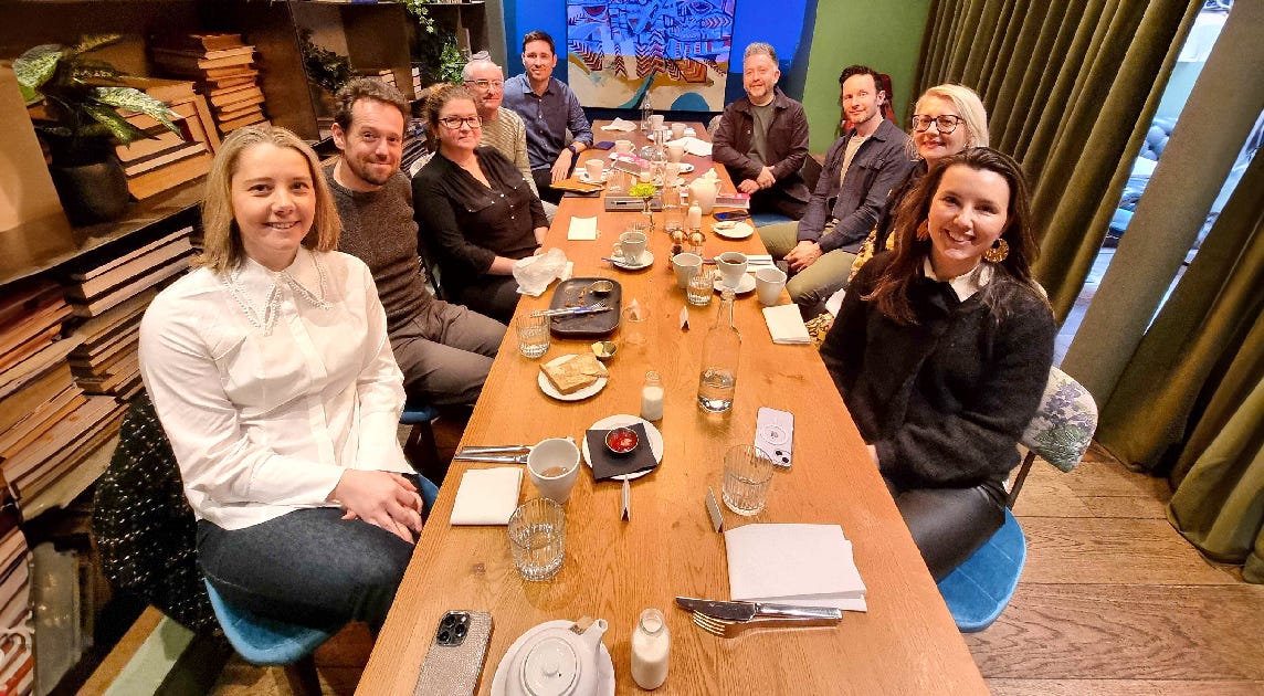 A group of people smiling, sitting around a long table