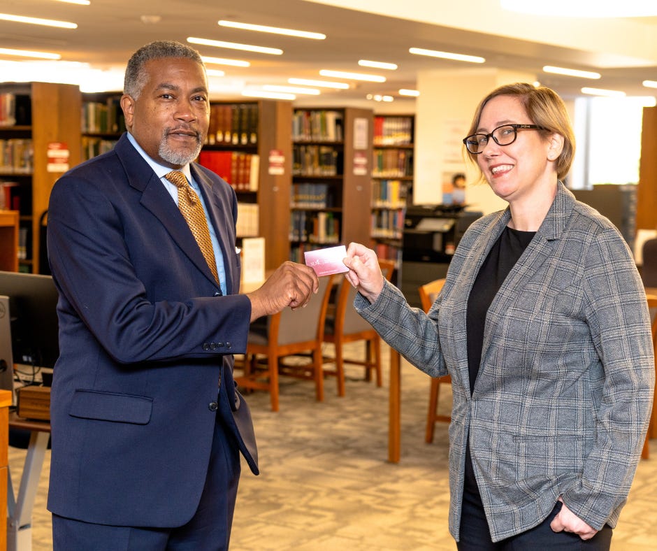   Michelle Underhill, State Librarian of North Carolina, presents Dr. Darin J. Waters, Deputy Secretary & Director of the Office of Archives and History, with an SLNC Government & Heritage Library card. 
