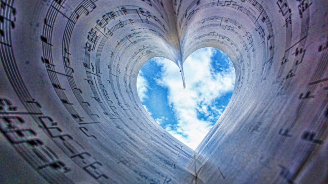 Sheet music whirls and swirls into an open heart. Through this portal, we can see the sky.