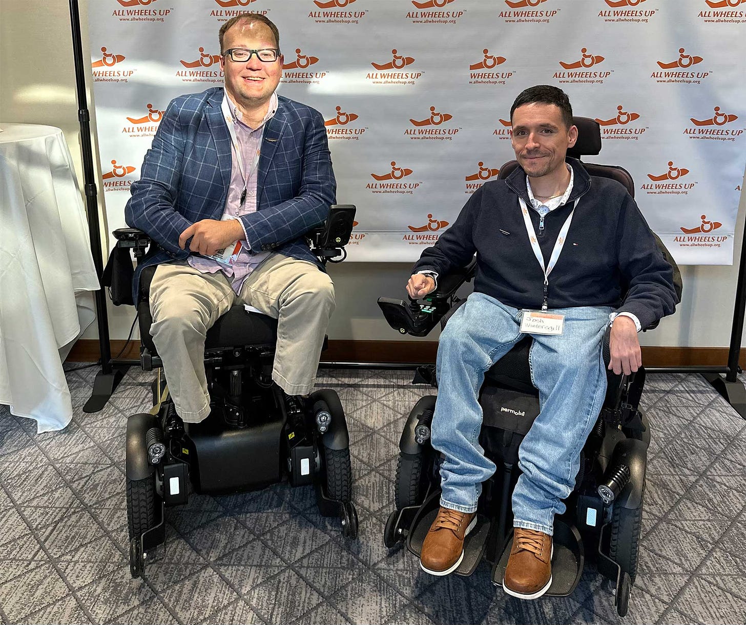 John pictured with Josh Wintersgill, both of whom are seated in their power wheelchairs.