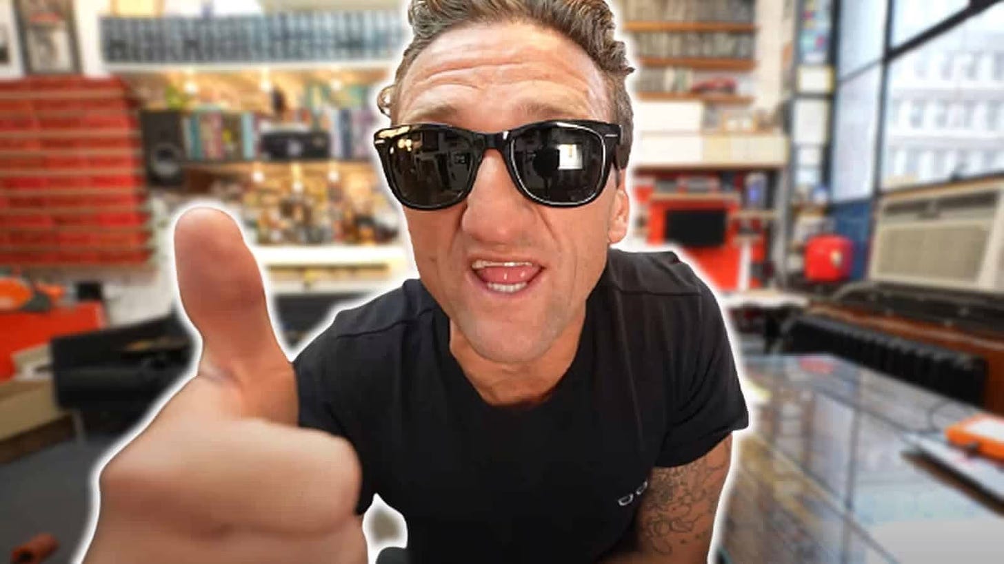 Casey Neistat in sunglasses with a thumbs up, in his studio