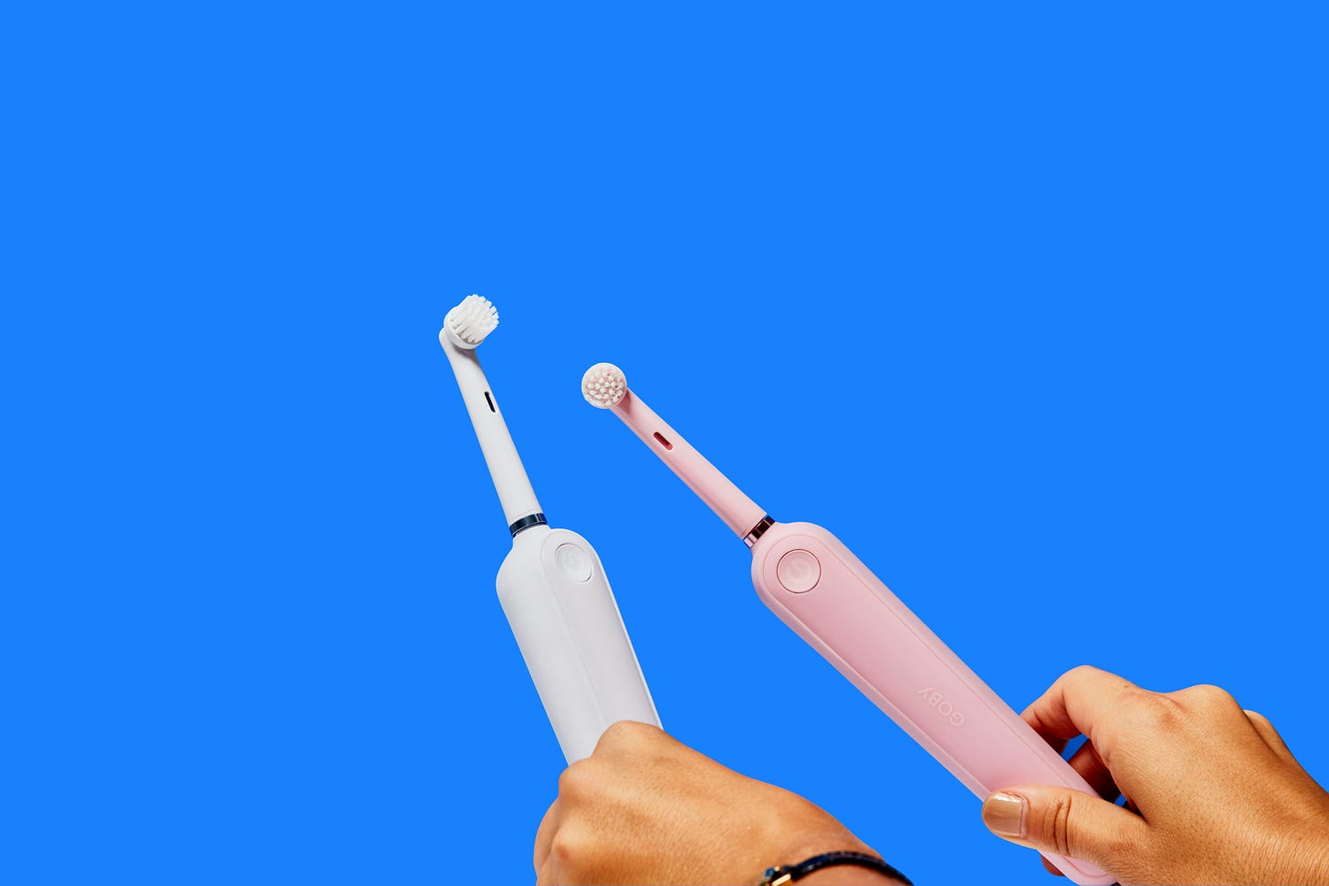 Two electric toothbrushes against a blue background