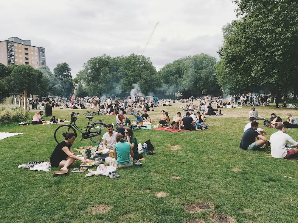 Summer 2016 in London Fields, there are young people sitting on the grass and some people using small barbecues