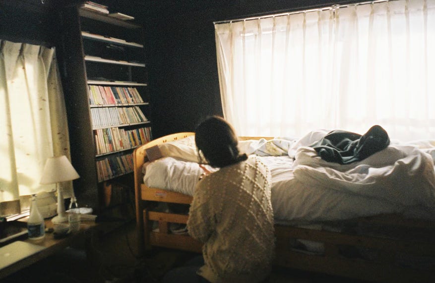 woman sitting by her bed, writing on the bed